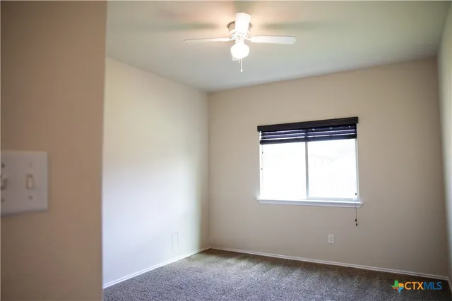 an empty room with a window and a fan