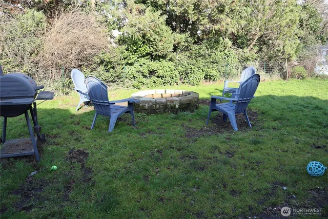 a view of a backyard with table and chairs a barbeque grill and a fire pit