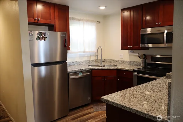 a kitchen with granite countertop a refrigerator and a sink