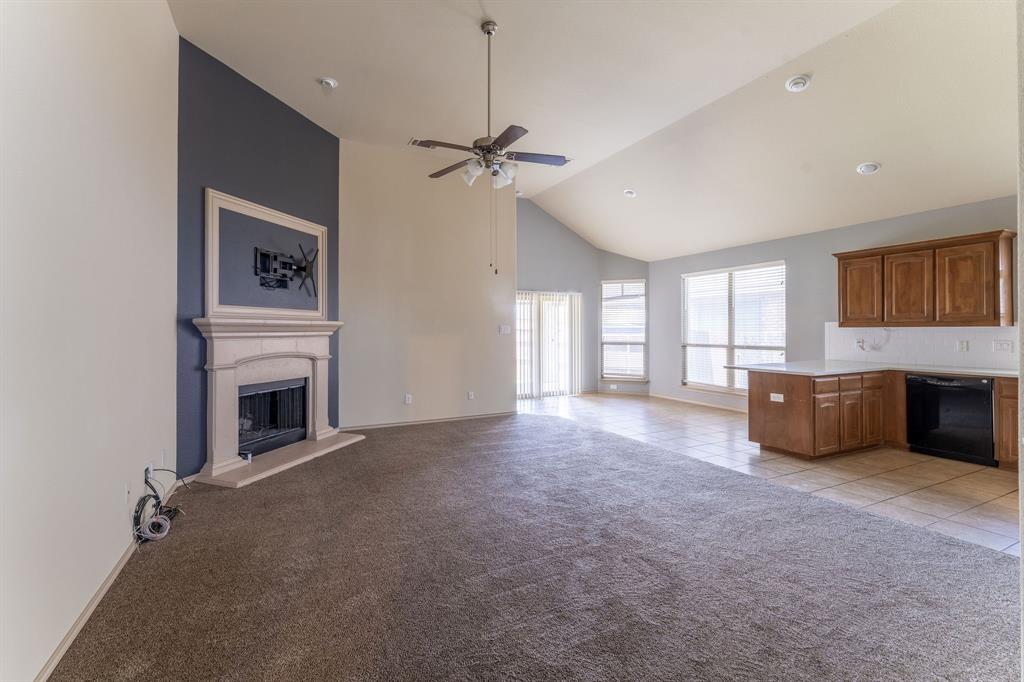 11156 Hawks Landing Road Fort Worth, TX 76052 - Photo 6 of 30 Open-concept living space featuring a vaulted ceiling and a stone-clad fireplace with a decorative mantel
