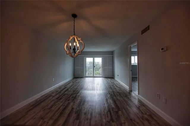 a view of a hallway with wooden floor and chandelier
