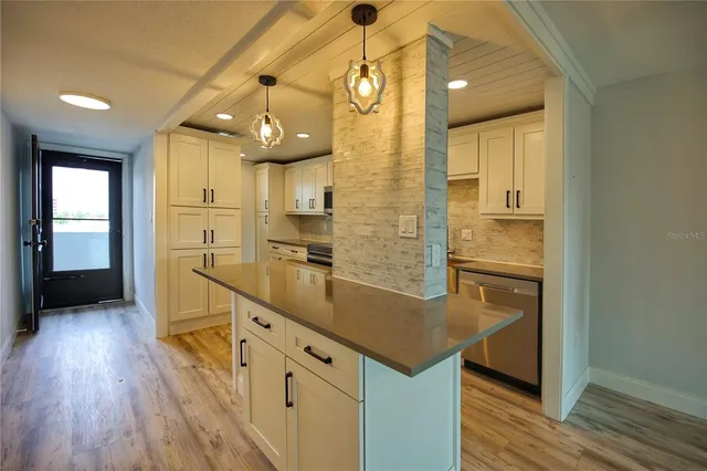 a kitchen with stainless steel appliances granite countertop a sink a refrigerator and a wooden floor