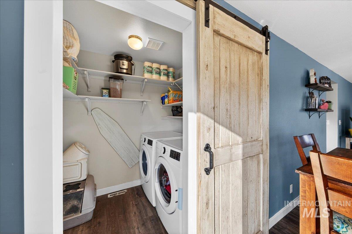 611 Northwest 15th Street Meridian, ID 83642 - Photo 12 of 35 Laundry area featuring a barn door, dark wood-style floors, and washing machine and clothes dryer