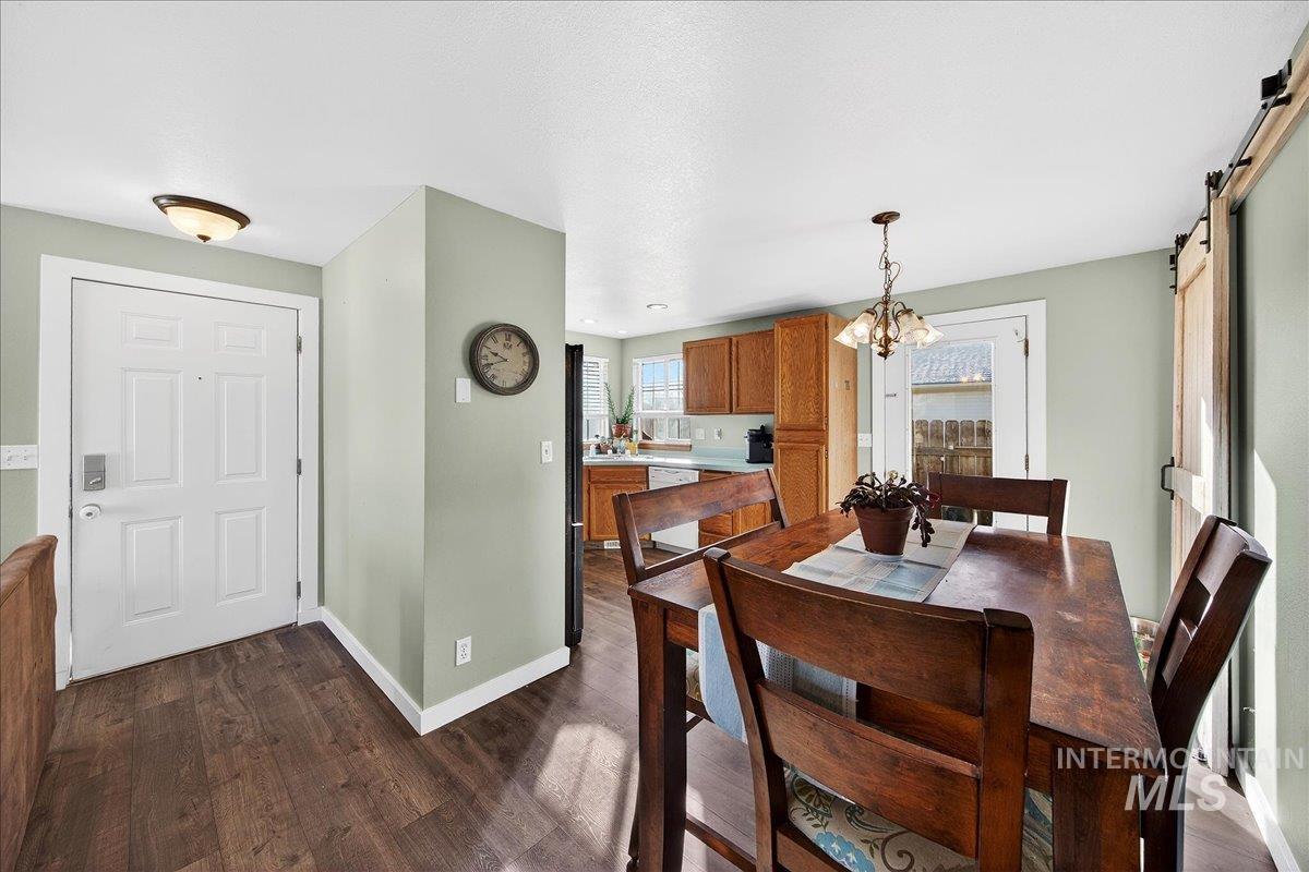 611 Northwest 15th Street Meridian, ID 83642 - Photo 6 of 35 Dining room featuring a barn door, dark wood-style floors, and a chandelier