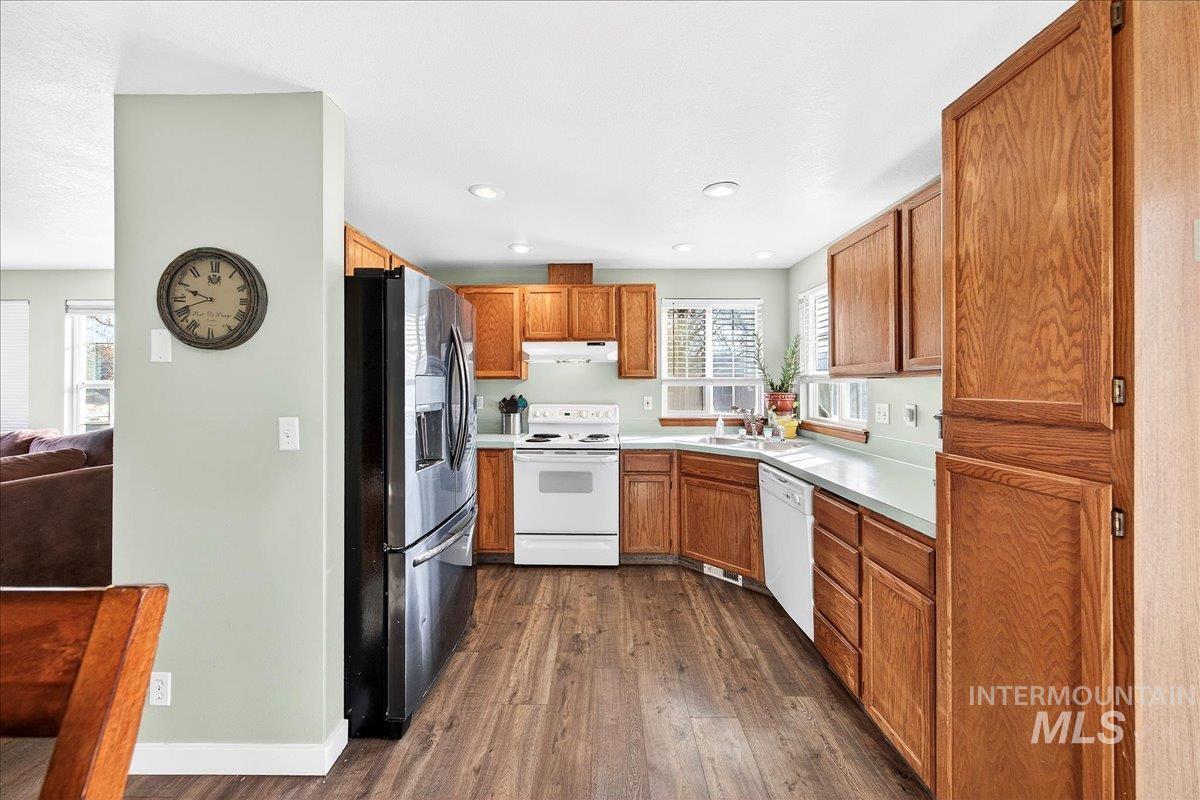 611 Northwest 15th Street Meridian, ID 83642 - Photo 7 of 35 Kitchen featuring white appliances, light countertops, dark wood-style flooring, brown cabinets, and recessed lighting