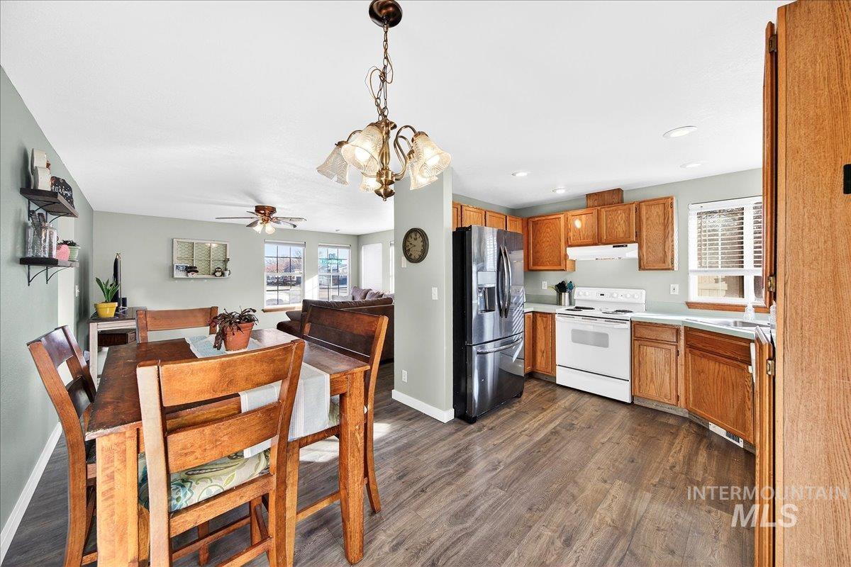 611 Northwest 15th Street Meridian, ID 83642 - Photo 8 of 35 Kitchen with stainless steel refrigerator with ice dispenser, white range with electric cooktop, light countertops, decorative light fixtures, and dark wood-style flooring