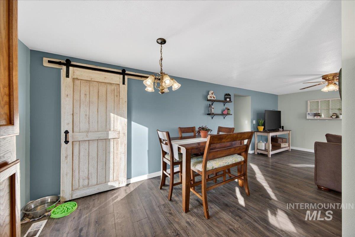 611 Northwest 15th Street Meridian, ID 83642 - Photo 10 of 35 Dining space featuring dark wood-style flooring, a barn door, a chandelier, and a ceiling fan