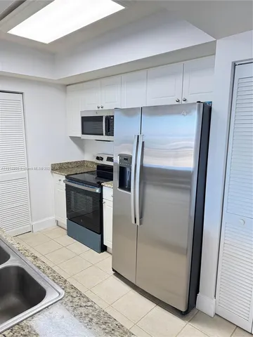 a kitchen with granite countertop a refrigerator and a sink
