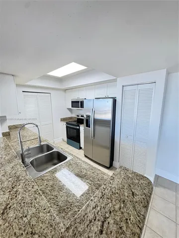 a kitchen with granite countertop a refrigerator and a sink