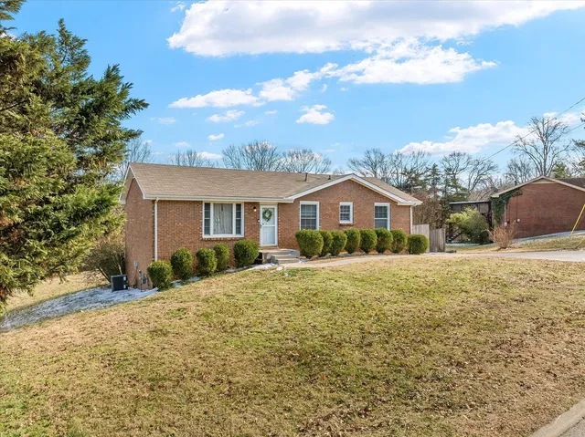 a front view of house with yard and trees in the background