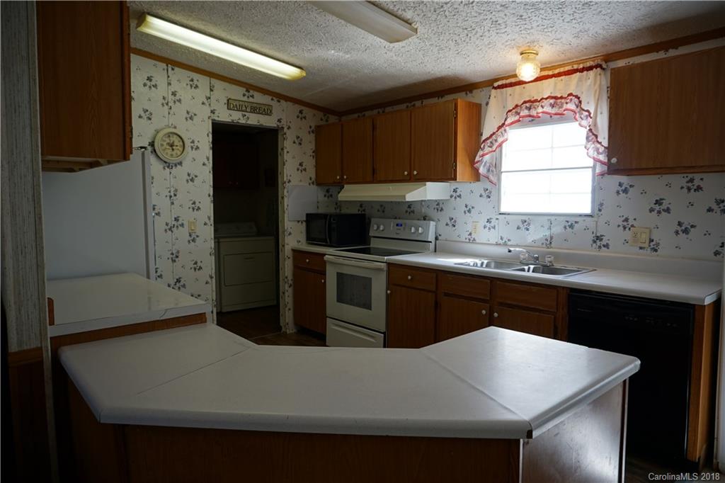 1042 Elliott Road Rutherfordton, NC 28139 - Photo 22 of 33 a kitchen with stainless steel appliances a sink a stove a refrigerator cabinets and a window