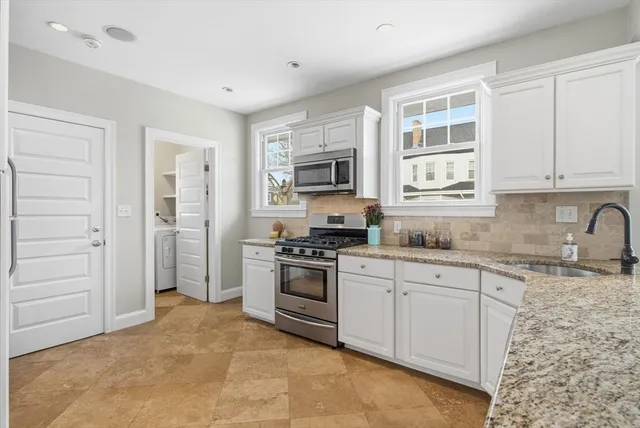 a kitchen with granite countertop a stove a sink and a refrigerator