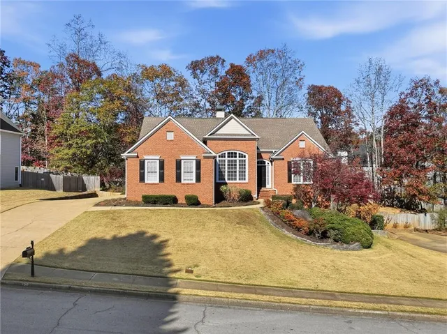 a front view of house with yard outdoor seating and covered with trees
