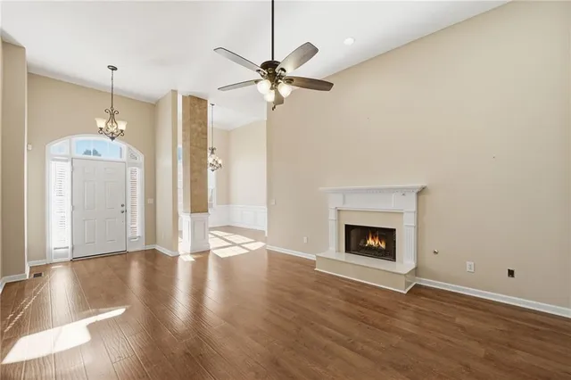a view of an empty room with wooden floor fireplace and a window
