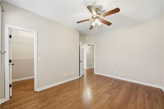 an empty room with wooden floor and ceiling fan