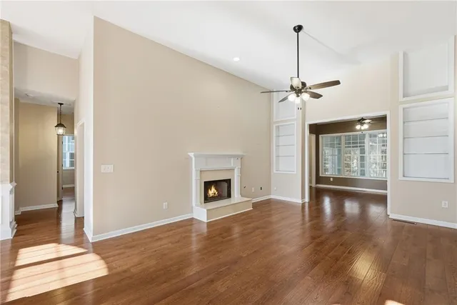 a view of an empty room with wooden floor and a fireplace