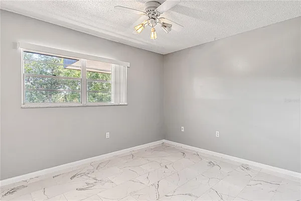an empty room with a window and ceiling fan