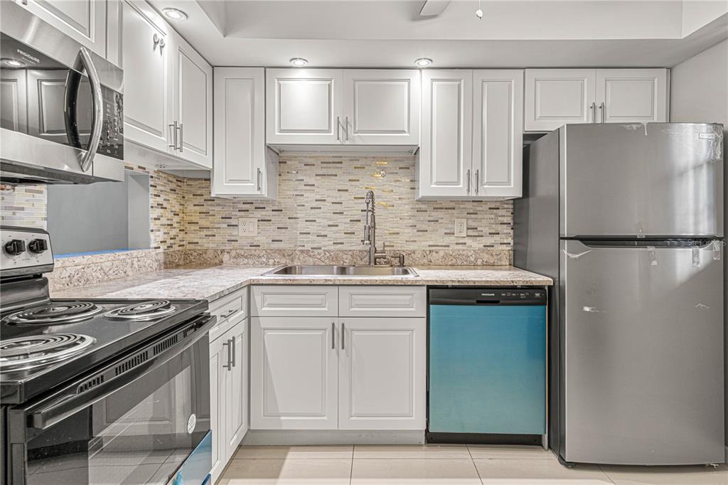 640 North Nova Road, Unit 409 Ormond Beach, FL 32174 - Photo 3 of 33 a kitchen with granite countertop a refrigerator stove top oven and sink