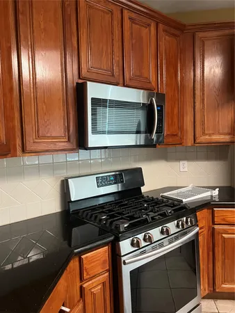 a kitchen with granite countertop cabinets stove top oven and microwave