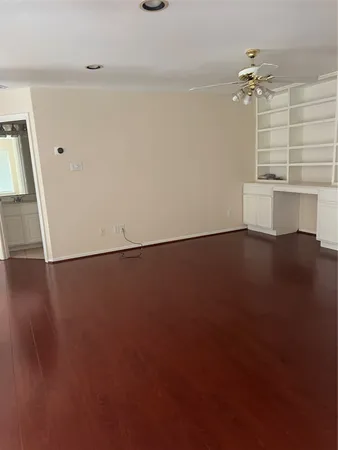 an empty room with wooden floor and a ceiling fan