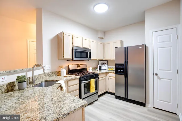 a kitchen with granite countertop a refrigerator a stove and a sink