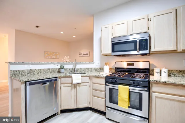 a kitchen with cabinets stainless steel appliances and a wooden floor