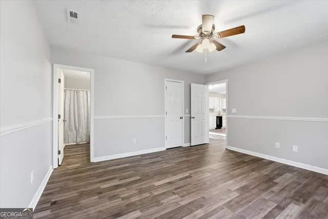an empty room with wooden floor ceiling fan and windows
