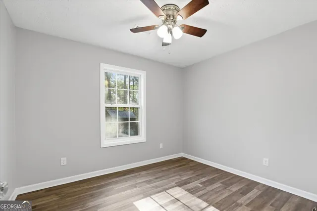 a view of an empty room with a window and wooden floor