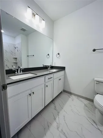a spacious bathroom with a granite countertop sink a toilet and a mirror