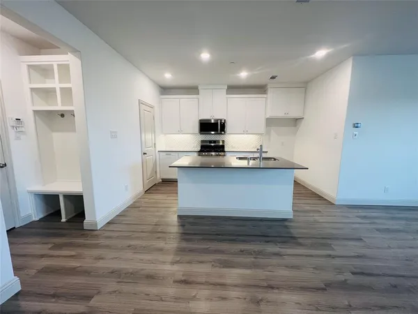a large kitchen with kitchen island a sink a stove a refrigerator and white cabinets