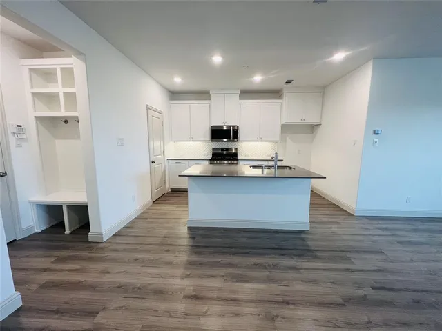 a large kitchen with kitchen island a sink a stove a refrigerator and white cabinets