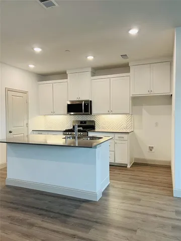 a kitchen with granite countertop a stove top oven sink and cabinets