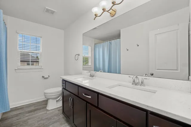 a bathroom with a granite countertop sink a toilet and a mirror