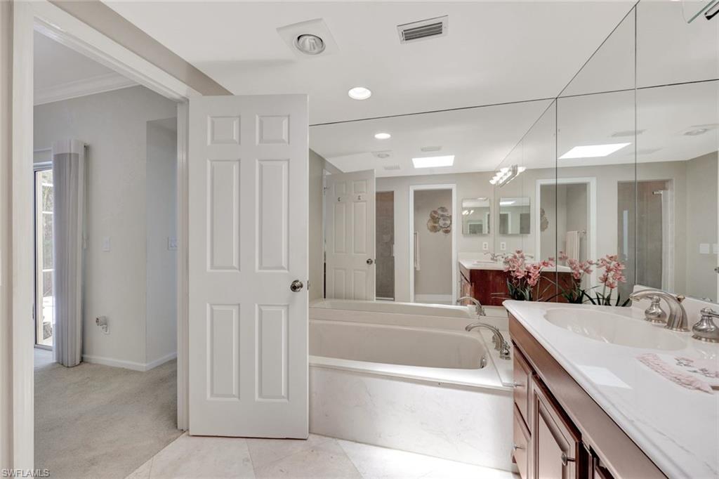 5929 Chanteclair Drive, Unit 8 Naples, FL 34108 - Photo 19 of 28 Bathroom with a garden tub, visible vents, a shower stall, vanity, and baseboards