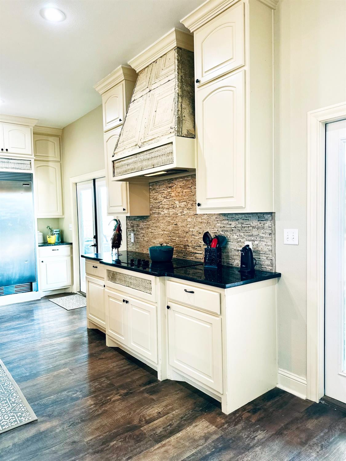 986 County Road 224 Post, TX 79356 - Photo 11 of 42 a kitchen with stainless steel appliances a stove a sink and white cabinets with wooden floor