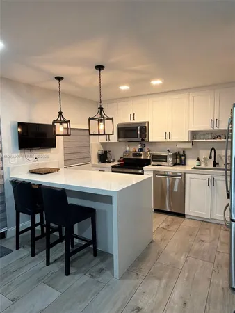 a kitchen with kitchen island a white counter top space cabinets and stainless steel appliances