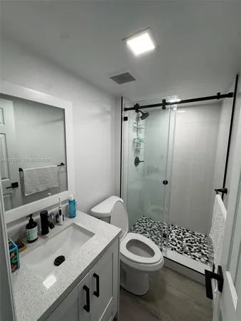 a bathroom with a sink a toilet a mirror and shower