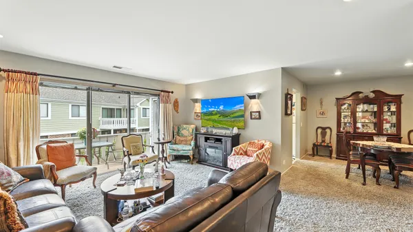 a living room with furniture a flat screen tv and floor to ceiling window