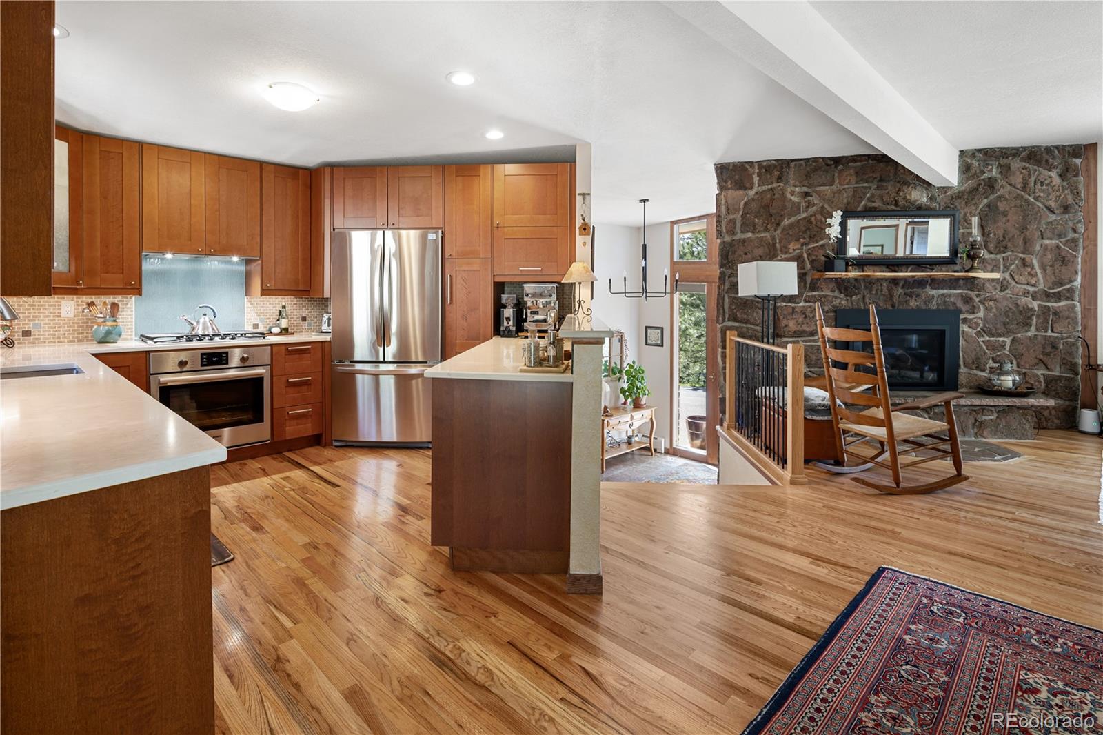 107 Elk Drive Evergreen, CO 80439 - Photo 2 of 45 a kitchen with stainless steel appliances granite countertop a refrigerator a stove top oven a dining table and chairs with wooden floor