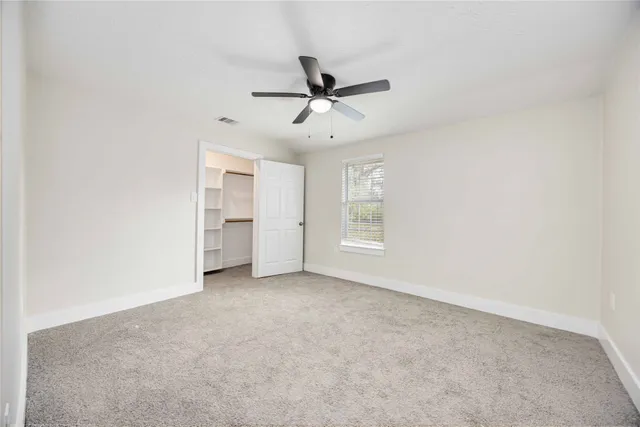 an empty room with a window and ceiling fan