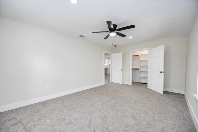 an empty room with closet and a ceiling fan
