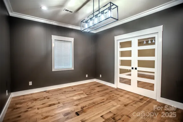 a view of an empty room with a window and wooden floor