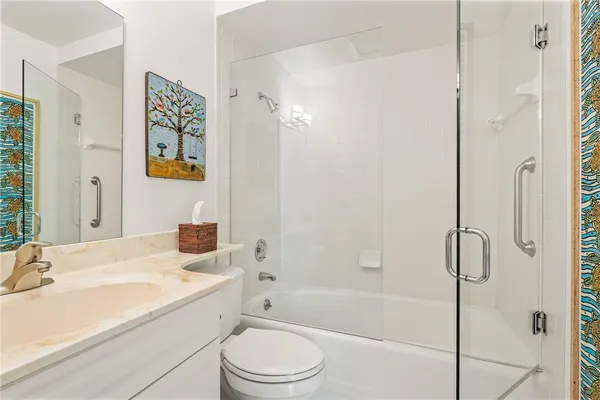 a bathroom with a granite countertop sink a toilet and shower