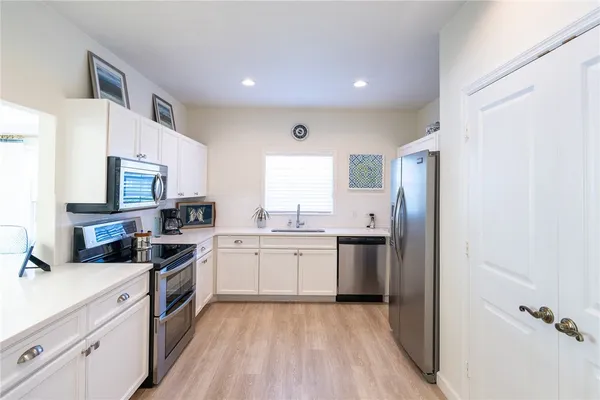 a kitchen with stainless steel appliances granite countertop a stove top oven a sink dishwasher and a refrigerator with wooden floor