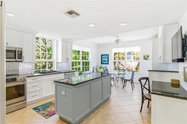 a kitchen with a stove a sink a kitchen island with chairs and cabinets