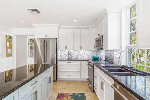 a kitchen with stainless steel appliances a sink stove refrigerator and cabinets