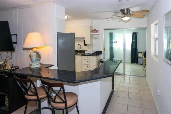 a kitchen with stainless steel appliances granite countertop a stove a refrigerator a sink a dining table and chairs with wooden floor