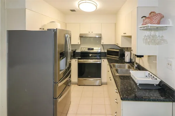 a kitchen with stainless steel appliances granite countertop a refrigerator a stove and a sink with wooden floor