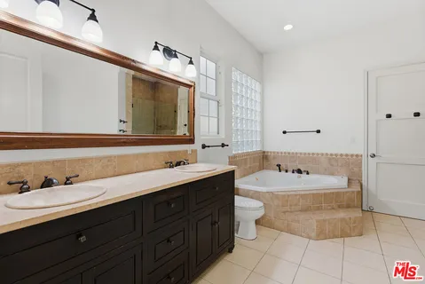 a bathroom with a double vanity sink mirror and bathtub