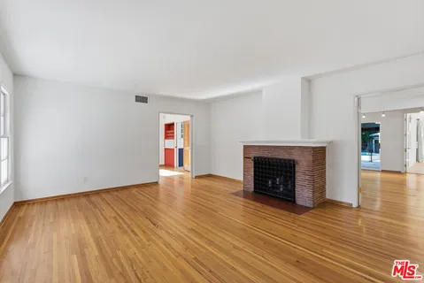 an empty room with wooden floor and fireplace